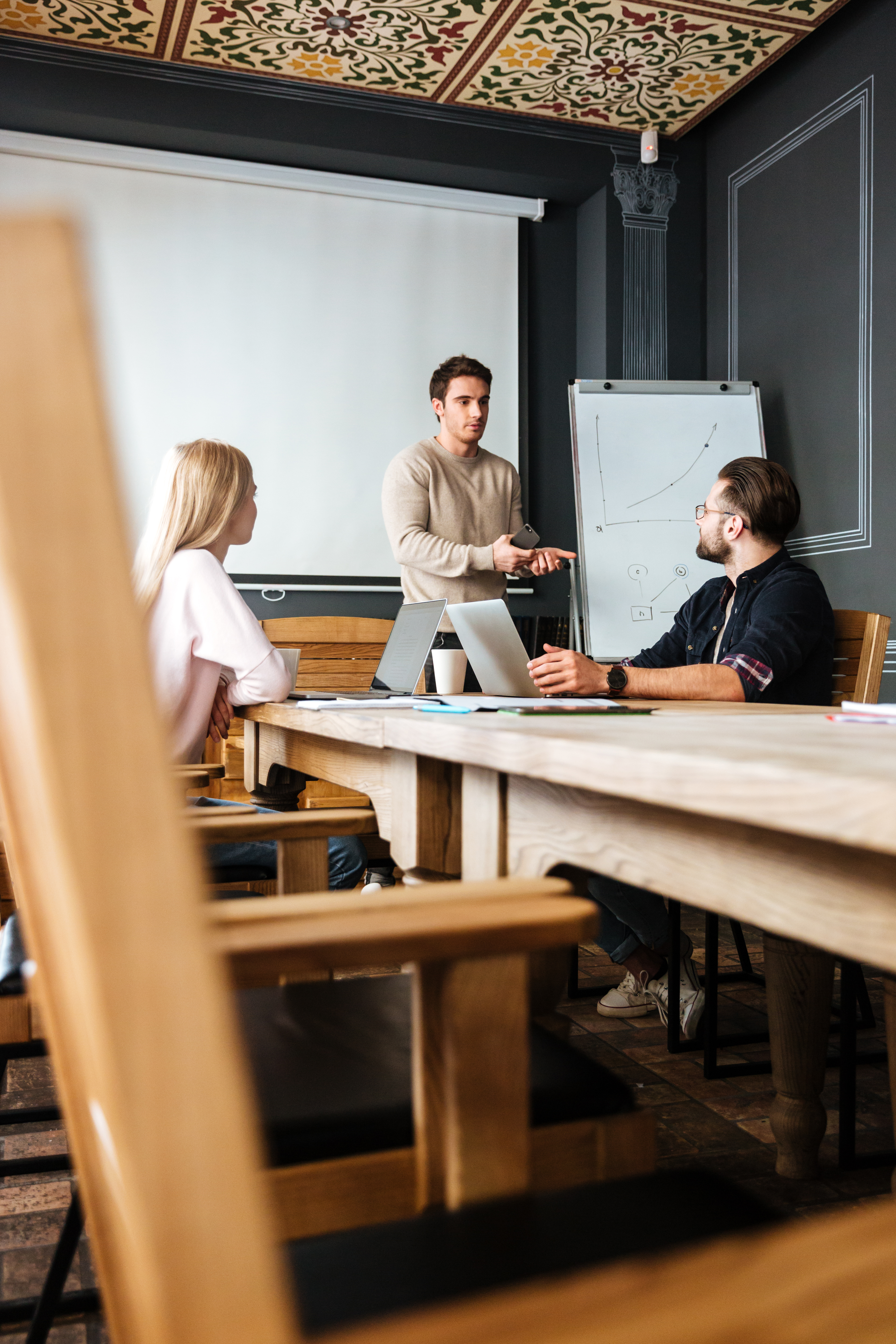 Diverse multiethnic business teamwork overworking in office meeting room analyzing financial graphs late at night. Coworkers brainstorming project ideas solving company problem.